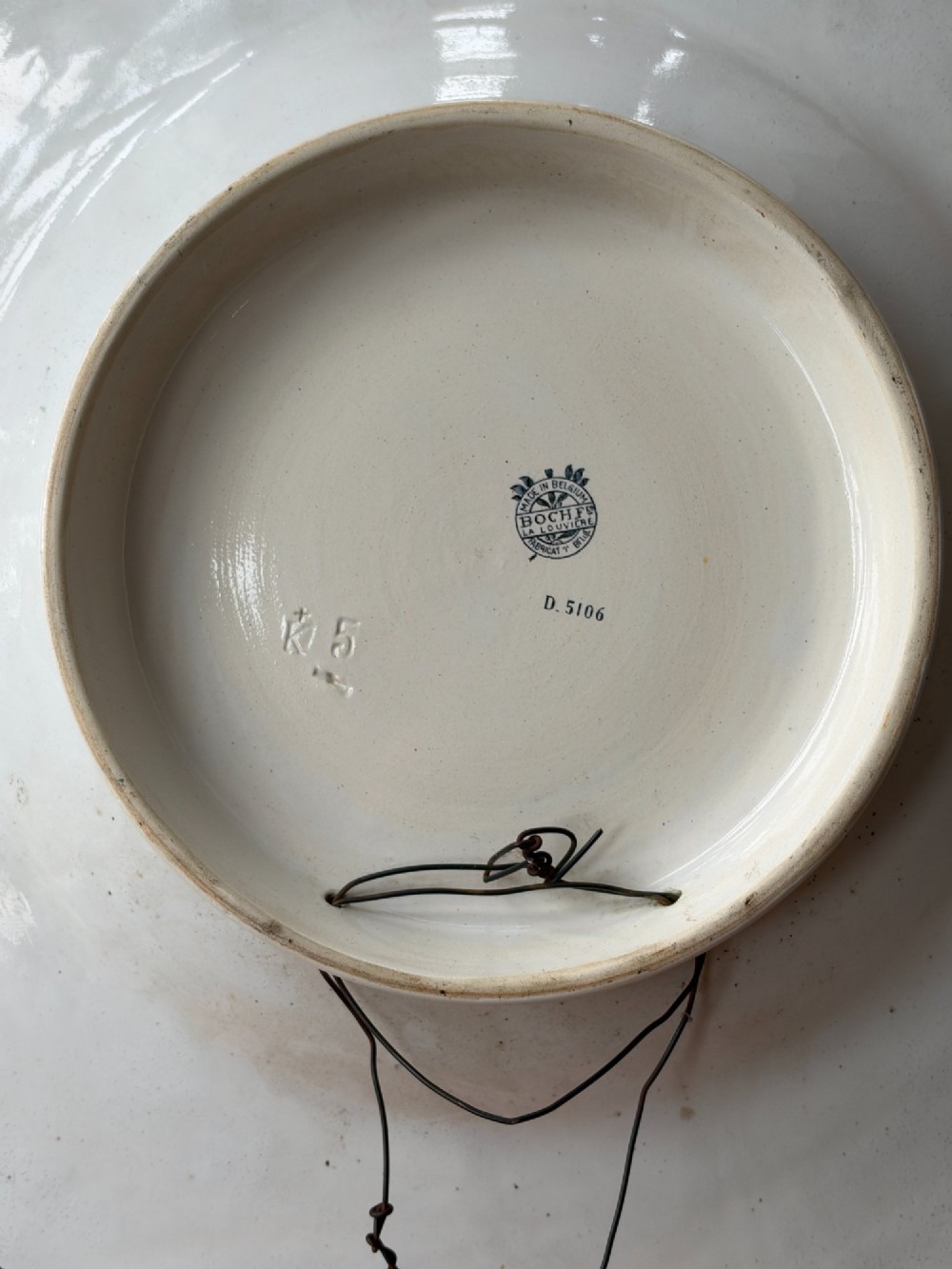 A circular Art Deco ceramic charger featuring radial segmented panels decorated with blue, turquoise, yellow, and white floral enamel patterns bordered in gold. View IX
