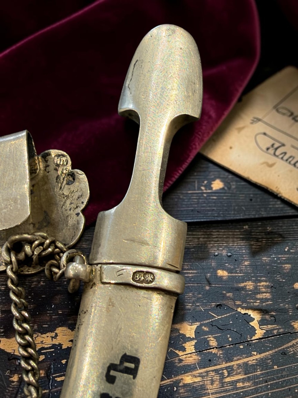 An antique Caucasian curved silver miniature dagger brooch featuring black niello scrollwork motifs and an attached suspension chain with a matching circular clasp. View XI