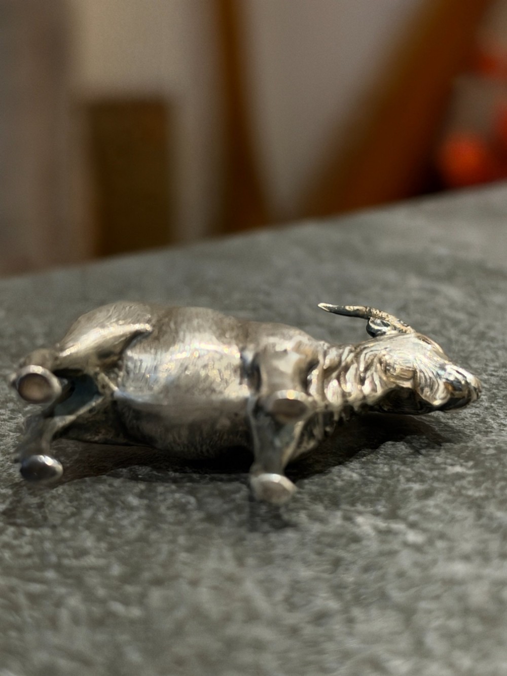 A small cast sterling silver miniature figurine of a billy goat displaying detailed fur texture, curved horns, and British hallmarks stamped along its side. View XIII