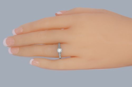 fig 1. An Art Deco diamond solitaire ring featuring a round central diamond flanked by geometric shoulders set with small accent diamonds in white gold and platinum.