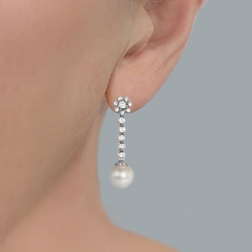 fig 1. A pair of 1960s 18ct white gold drop earrings featuring floral diamond cluster tops above linear diamond links and round white pearls.