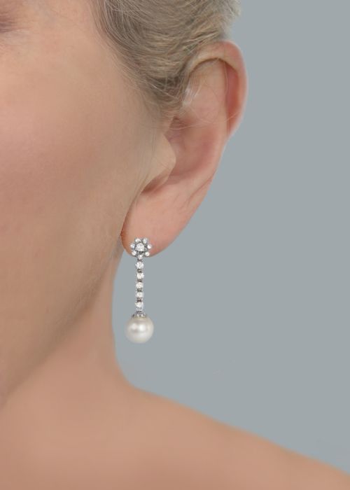 fig 5. A pair of 1960s 18ct white gold drop earrings featuring floral diamond cluster tops above linear diamond links and round white pearls.