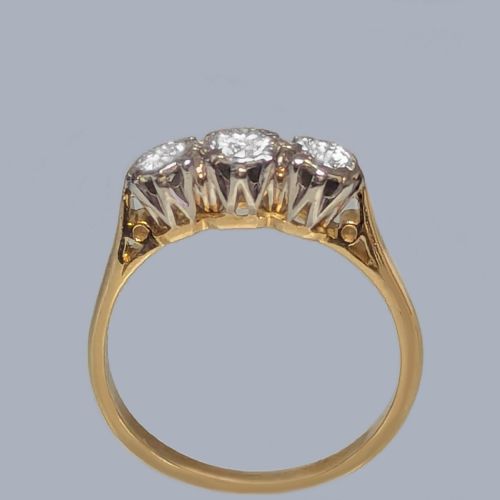 fig 2. A three-stone round diamond trilogy ring set in white metal claw mounts on an 18ct yellow gold band.