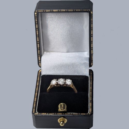 fig 6. A three-stone round diamond trilogy ring set in white metal claw mounts on an 18ct yellow gold band.