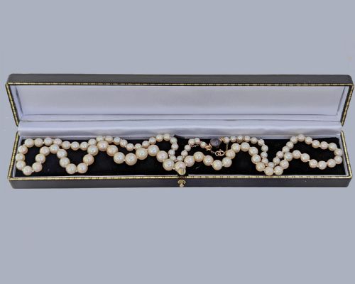 fig 5. A long single strand of graduated white cultured pearls featuring an 18ct gold clasp with a dark accent pearl and safety chain.