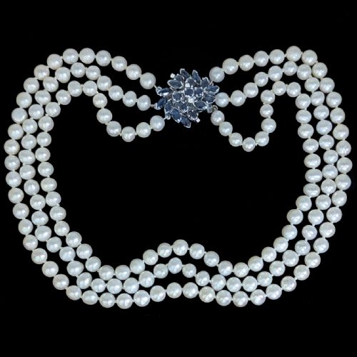 fig 4. A vintage three-strand white pearl necklace joined by a silver floral clasp set with marquise-cut blue sapphires and small diamonds.