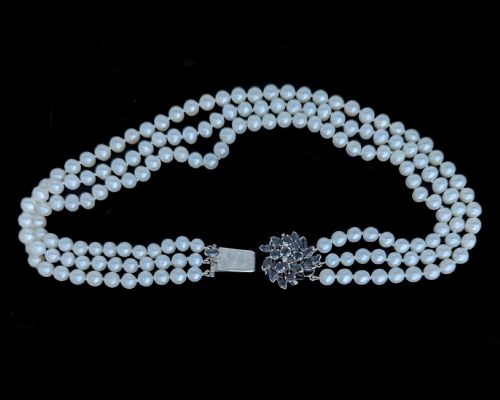 fig 6. A vintage three-strand white pearl necklace joined by a silver floral clasp set with marquise-cut blue sapphires and small diamonds.