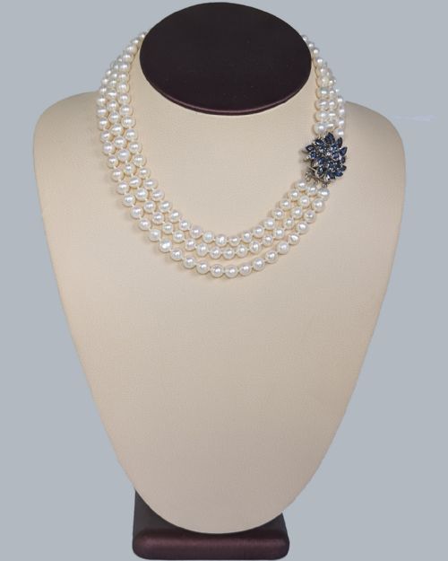 fig 11. A vintage three-strand white pearl necklace joined by a silver floral clasp set with marquise-cut blue sapphires and small diamonds.