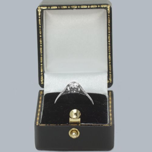 fig 5. An 18ct white gold solitaire ring showcasing a central round diamond in a claw setting flanked by small diamonds in the shoulders.