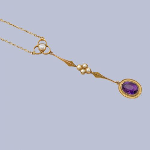 fig 1. An Edwardian 9ct gold drop necklace featuring a fine chain suspending an elongated linear pendant set with seed pearls and an oval-cut amethyst.