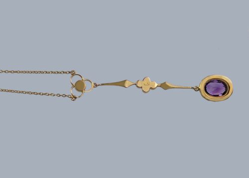 fig 2. An Edwardian 9ct gold drop necklace featuring a fine chain suspending an elongated linear pendant set with seed pearls and an oval-cut amethyst.