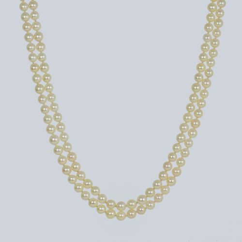 fig 3. A double strand cultured pearl necklace featuring uniform cream pearls fastened with a round 9ct gold clasp inset with a dark red garnet stone.