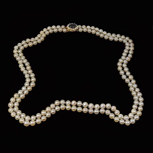 fig 4. A double strand cultured pearl necklace featuring uniform cream pearls fastened with a round 9ct gold clasp inset with a dark red garnet stone.