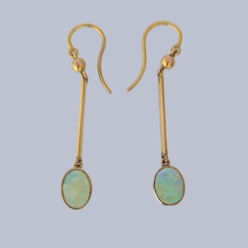 fig 3. A pair of vintage 18 carat yellow gold drop earrings featuring slender vertical bars suspended from wire hooks and terminating in oval opal cabochons displaying blue and green play-of-colour within milgrain settings.