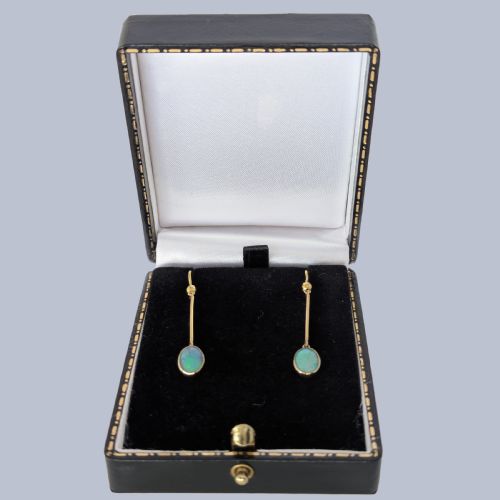 fig 5. A pair of vintage 18 carat yellow gold drop earrings featuring slender vertical bars suspended from wire hooks and terminating in oval opal cabochons displaying blue and green play-of-colour within milgrain settings.
