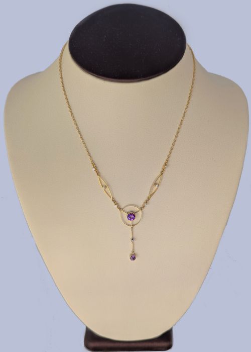 fig 5. An Edwardian 18ct gold lavalier necklace featuring openwork geometric wire loops set with small diamonds, a central round bezel-set amethyst, and a vertical drop terminating in a second amethyst stone.