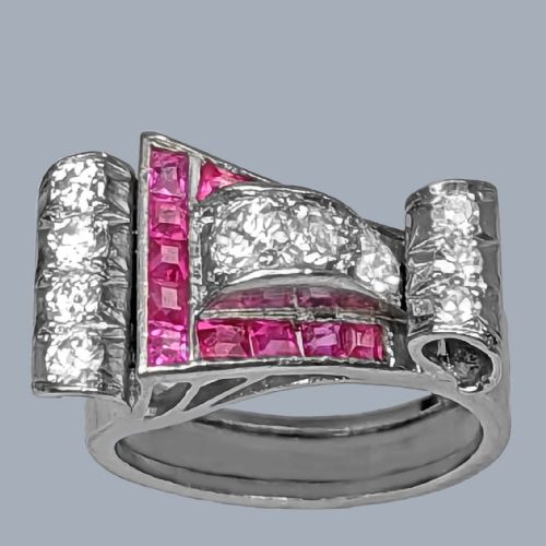 fig 3. A platinum Art Deco buckle ring featuring channel-set red rubies and pave-set old cut diamonds forming a curved scroll motif.