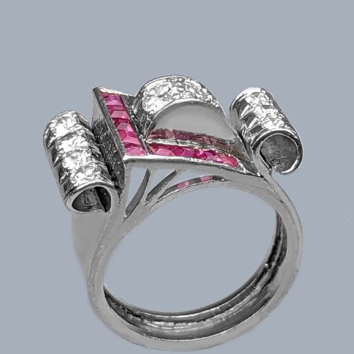fig 6. A platinum Art Deco buckle ring featuring channel-set red rubies and pave-set old cut diamonds forming a curved scroll motif.