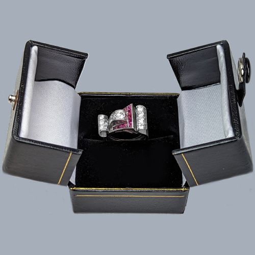 fig 8. A platinum Art Deco buckle ring featuring channel-set red rubies and pave-set old cut diamonds forming a curved scroll motif.