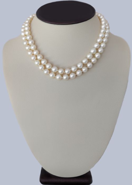 fig 2. A double strand cream pearl necklace featuring a square 18ct white gold clasp set with a central square blue sapphire and accent diamonds.