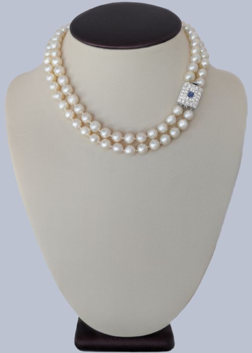 fig 3. A double strand cream pearl necklace featuring a square 18ct white gold clasp set with a central square blue sapphire and accent diamonds.