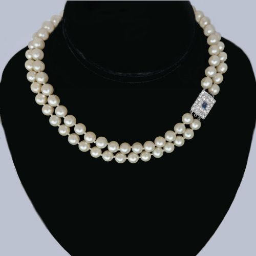 fig 8. A double strand cream pearl necklace featuring a square 18ct white gold clasp set with a central square blue sapphire and accent diamonds.