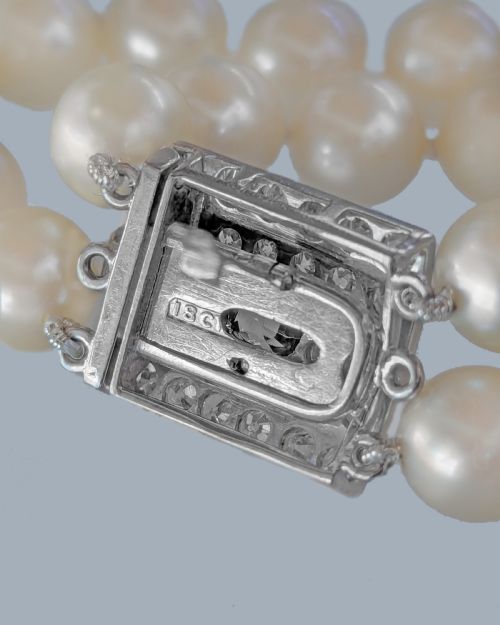 fig 9. A double strand cream pearl necklace featuring a square 18ct white gold clasp set with a central square blue sapphire and accent diamonds.