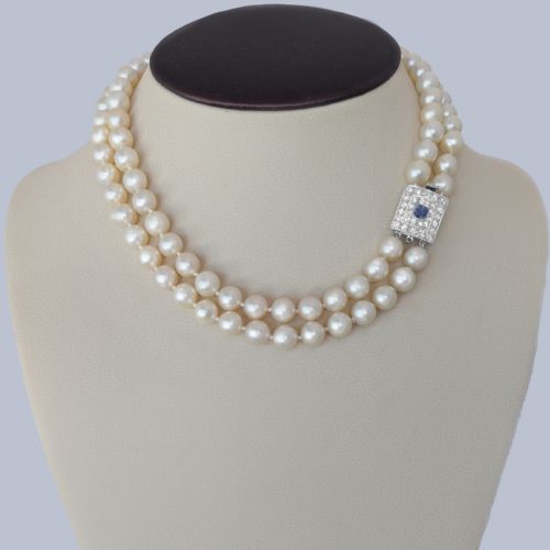 fig 10. A double strand cream pearl necklace featuring a square 18ct white gold clasp set with a central square blue sapphire and accent diamonds.
