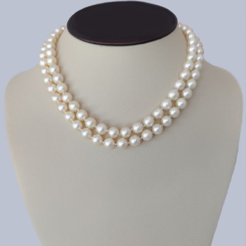 fig 11. A double strand cream pearl necklace featuring a square 18ct white gold clasp set with a central square blue sapphire and accent diamonds.
