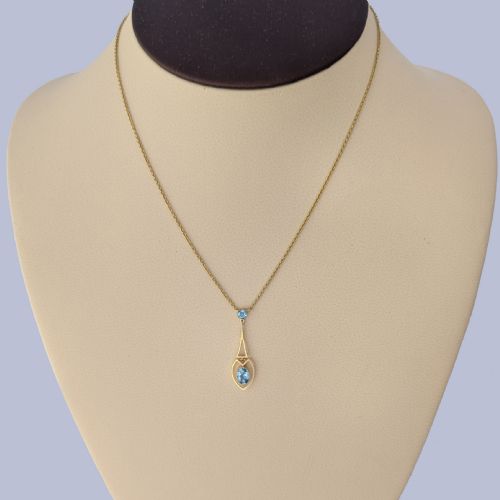 fig 1. An Edwardian 15ct yellow gold drop pendant featuring a round aquamarine stone above an openwork heart-shaped frame housing an oval aquamarine gemstone on a fine link chain.