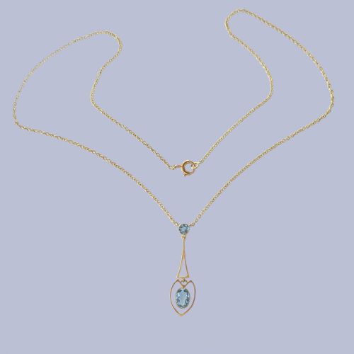 fig 3. An Edwardian 15ct yellow gold drop pendant featuring a round aquamarine stone above an openwork heart-shaped frame housing an oval aquamarine gemstone on a fine link chain.