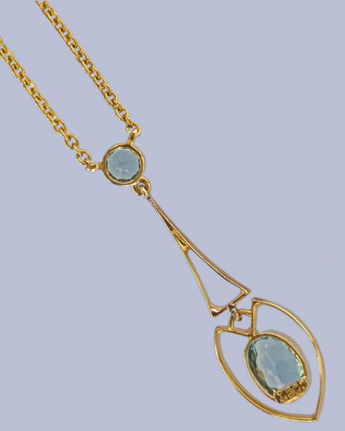 fig 4. An Edwardian 15ct yellow gold drop pendant featuring a round aquamarine stone above an openwork heart-shaped frame housing an oval aquamarine gemstone on a fine link chain.