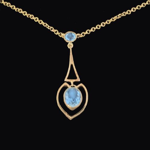 fig 5. An Edwardian 15ct yellow gold drop pendant featuring a round aquamarine stone above an openwork heart-shaped frame housing an oval aquamarine gemstone on a fine link chain.