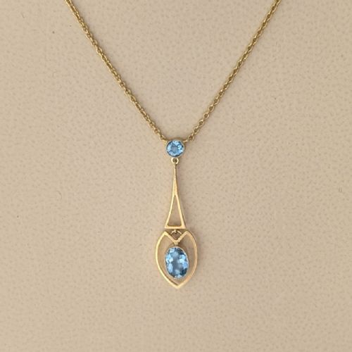 fig 6. An Edwardian 15ct yellow gold drop pendant featuring a round aquamarine stone above an openwork heart-shaped frame housing an oval aquamarine gemstone on a fine link chain.