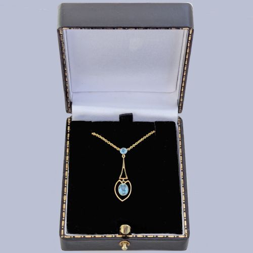 fig 7. An Edwardian 15ct yellow gold drop pendant featuring a round aquamarine stone above an openwork heart-shaped frame housing an oval aquamarine gemstone on a fine link chain.