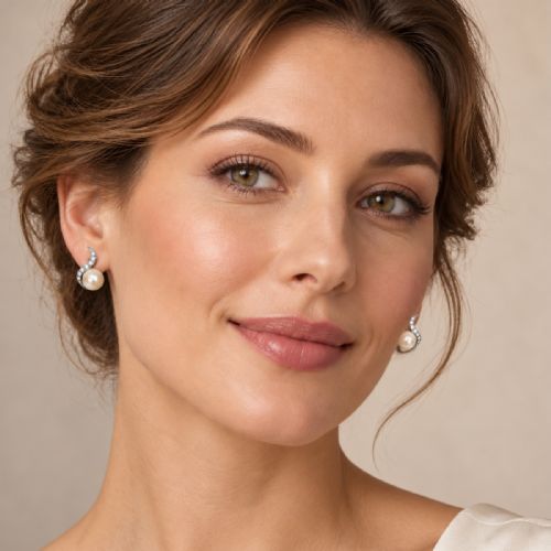 fig 1. A pair of 18ct white gold stud earrings featuring round cream pearls accented with sweeping bands of grain-set diamonds.