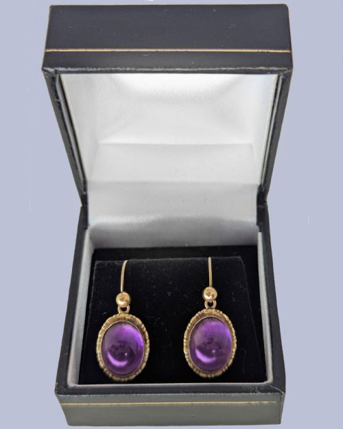 fig 3. Pair of vintage 9ct gold drop earrings featuring oval cabochon purple amethysts set in decorative gold borders with shepherds hook wires.
