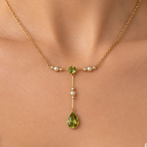 fig 2. An Edwardian 15ct gold lavalier pendant necklace featuring a central round peridot, seed pearl accents, and a suspended pear-cut peridot drop.