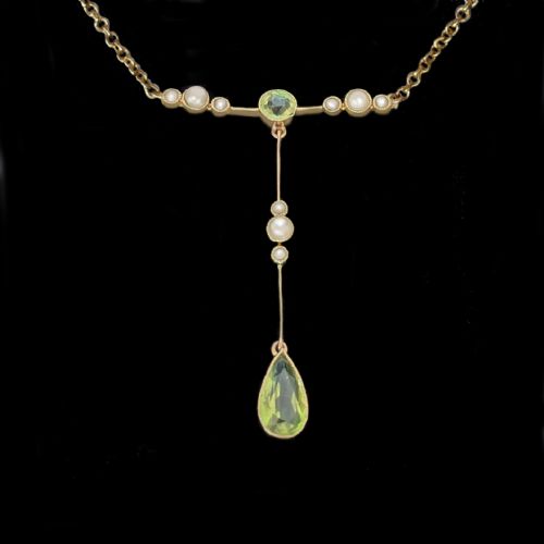 fig 3. An Edwardian 15ct gold lavalier pendant necklace featuring a central round peridot, seed pearl accents, and a suspended pear-cut peridot drop.