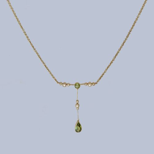 fig 5. An Edwardian 15ct gold lavalier pendant necklace featuring a central round peridot, seed pearl accents, and a suspended pear-cut peridot drop.