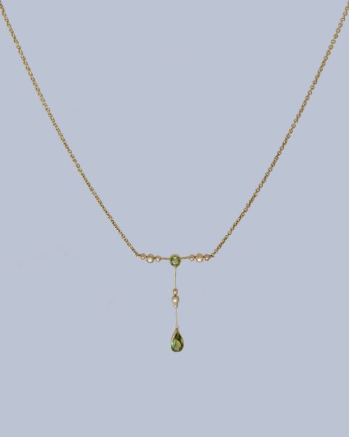 fig 6. An Edwardian 15ct gold lavalier pendant necklace featuring a central round peridot, seed pearl accents, and a suspended pear-cut peridot drop.