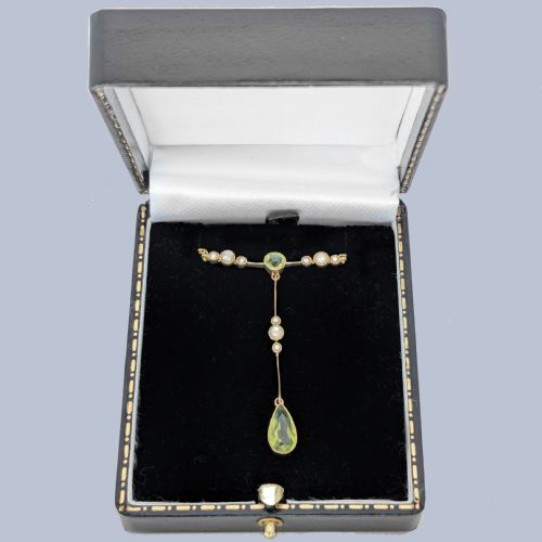 fig 7. An Edwardian 15ct gold lavalier pendant necklace featuring a central round peridot, seed pearl accents, and a suspended pear-cut peridot drop.