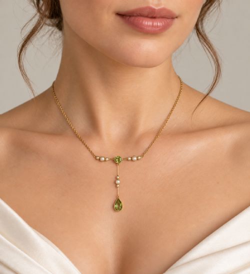 fig 8. An Edwardian 15ct gold lavalier pendant necklace featuring a central round peridot, seed pearl accents, and a suspended pear-cut peridot drop.