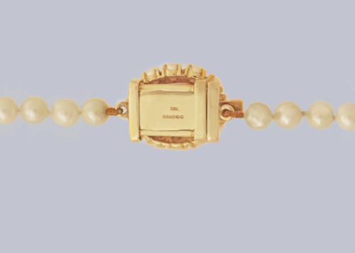 fig 4. A single strand of cream cultured pearls featuring an oval purple amethyst mounted in a 9ct gold clasp surrounded by small pearls.