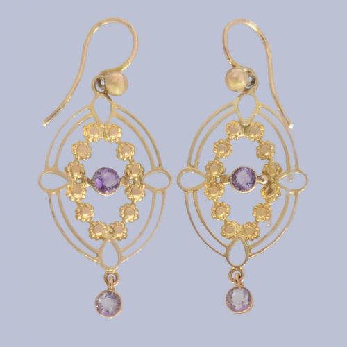 fig 1. A pair of Edwardian 9ct gold drop earrings featuring an openwork oval frame, a central round amethyst, floral details, and a dangling amethyst bottom drop.