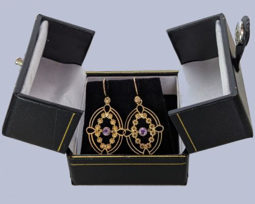 fig 3. A pair of Edwardian 9ct gold drop earrings featuring an openwork oval frame, a central round amethyst, floral details, and a dangling amethyst bottom drop.