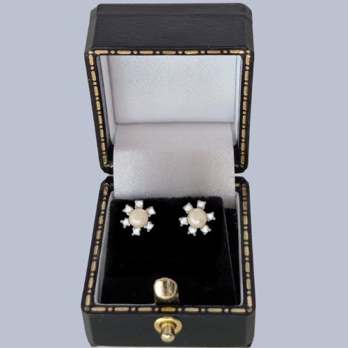 fig 5. A pair of 18ct white gold stud earrings featuring a central cream pearl surrounded by six claw-set diamonds in a floral cluster arrangement.