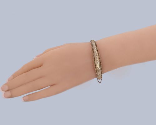 fig 4. An Edwardian 9ct rose gold hinged bangle with foliate engraving, beaded border trim, and a safety chain.