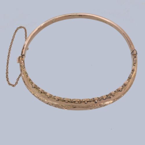 fig 5. An Edwardian 9ct rose gold hinged bangle with foliate engraving, beaded border trim, and a safety chain.