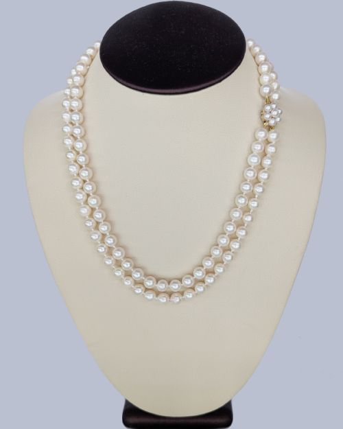 fig 3. A double-strand cultured pearl necklace featuring uniform cream pearls fastened with a floral cluster gold clasp.